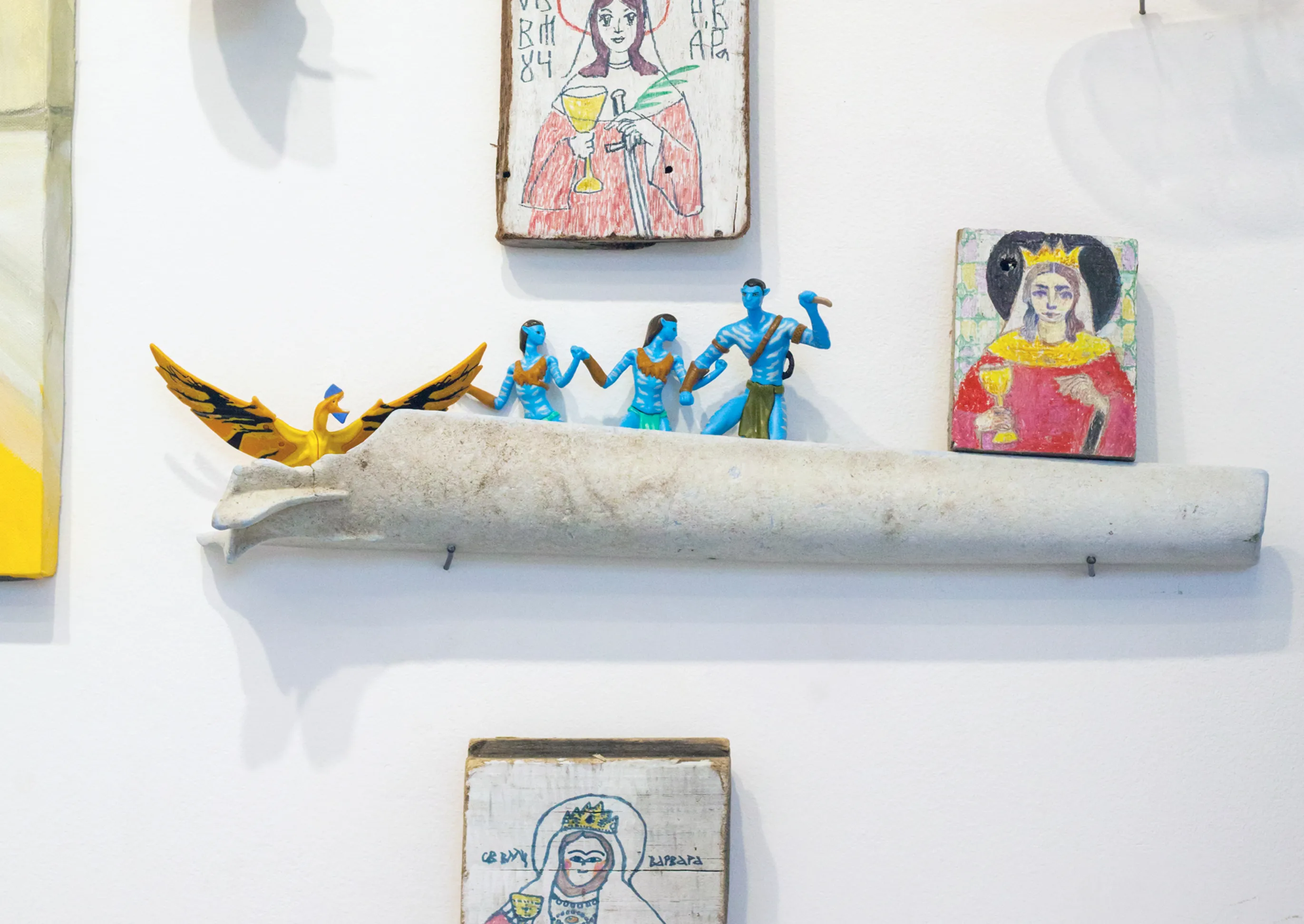 Detail of hand-painted folk icon boards, small painted figurines, and a golden bird ornament on a shelf