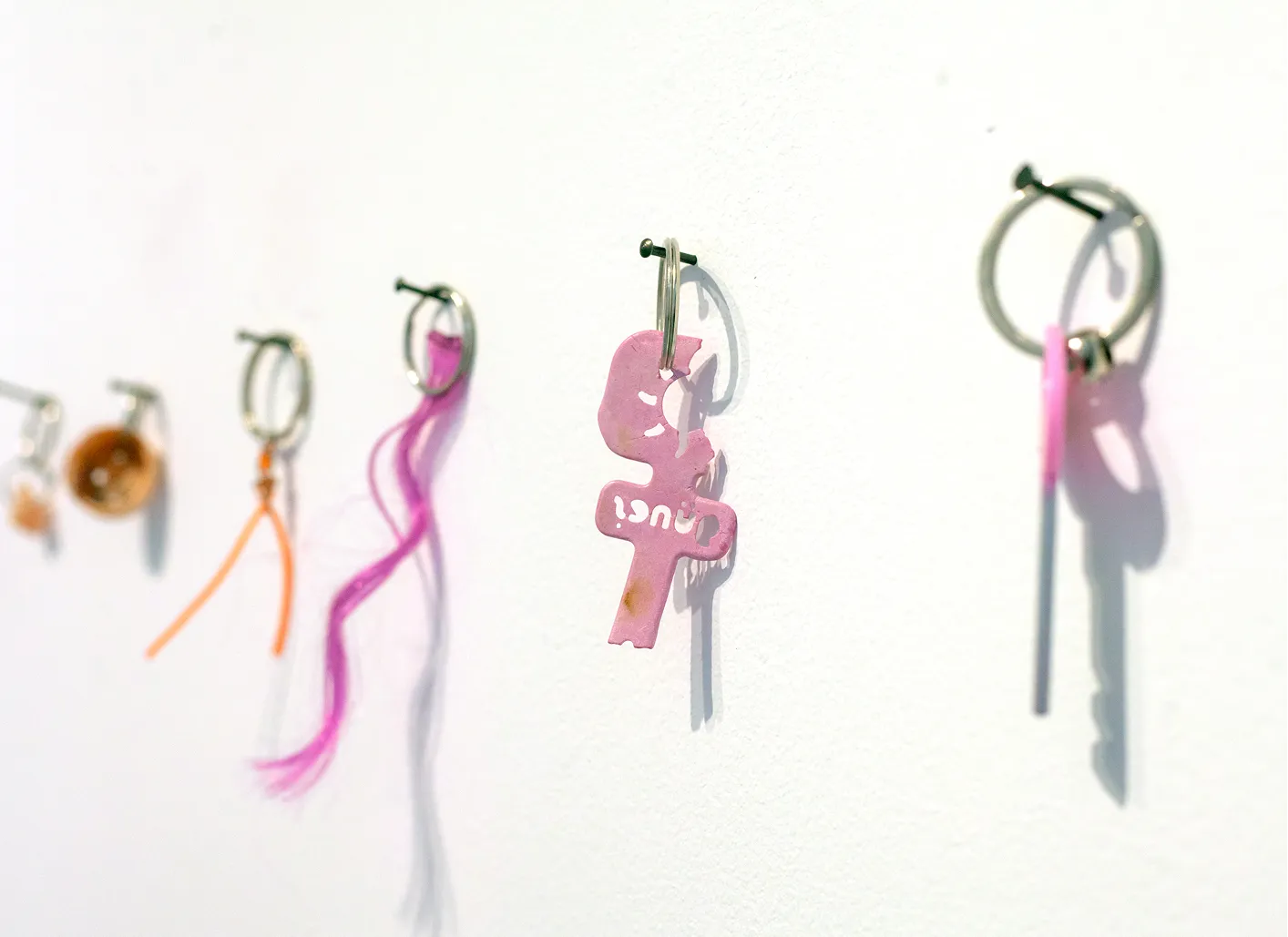 Detail of small trinkets, keys, and hair strands hung from nails on the wall