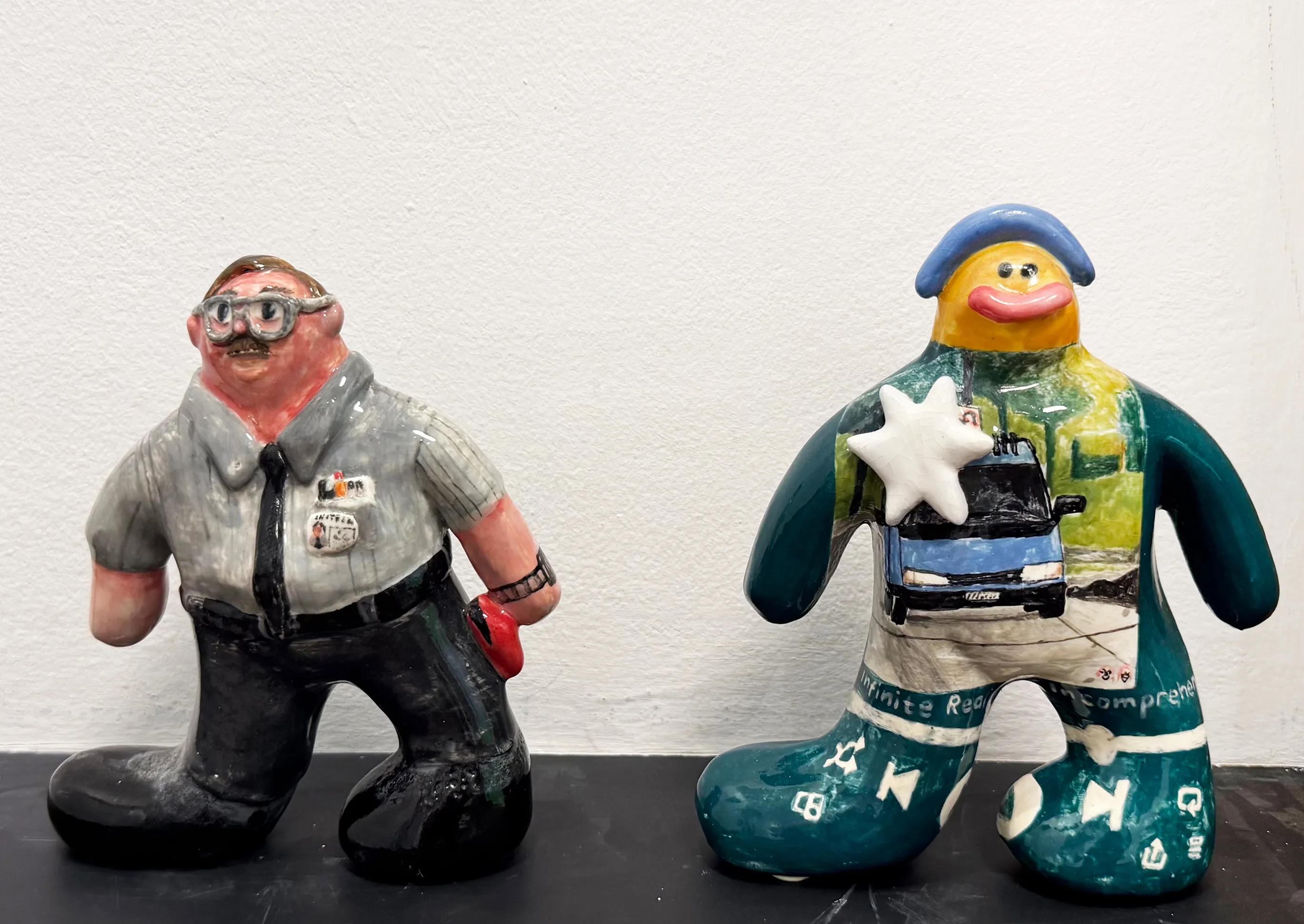 Two glazed standing figures, a uniformed guard and an armored creature, on a low shelf