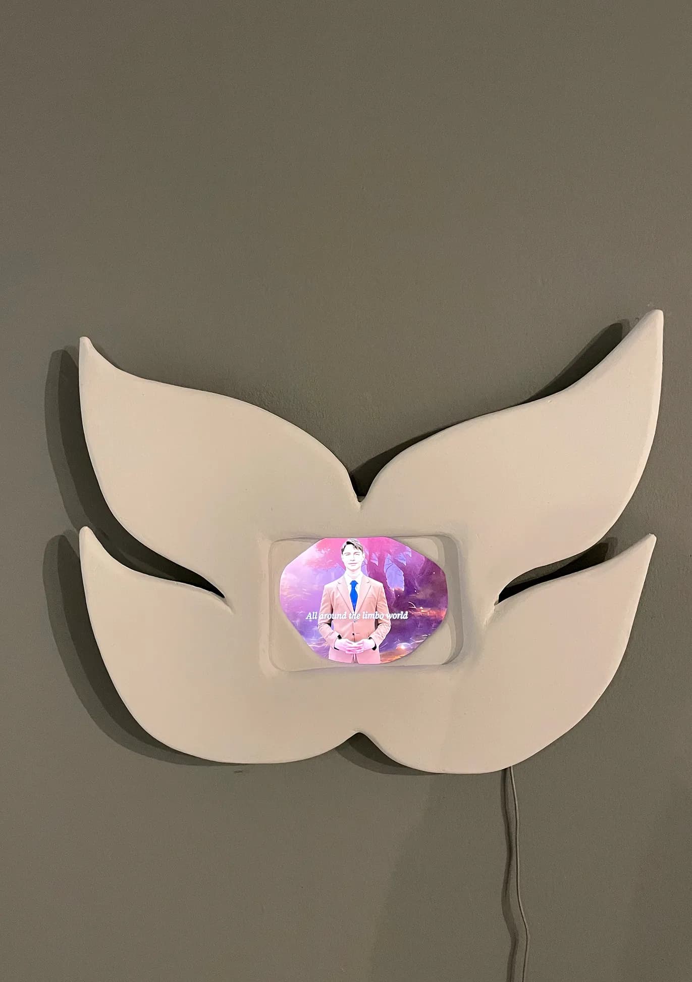 Wall-mounted sculptural mask with an embedded video screen